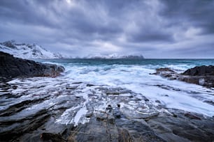 Waves of Norwegian sea crushing at rocky coast in fjord. Vikten, Lofoten islands, Norway