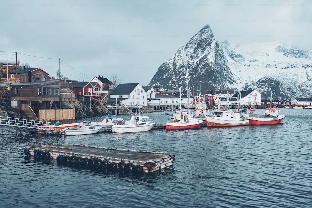 Pier mit Schiffen im Fischerdorf Hamnoy auf den Lofoten, Norwegen mit roten Rorbuhäusern im Winter