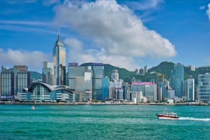 HONG KONG, CHINA - MAY 1, 2018: Boat in Victoria Harbour and Hong Kong skyline cityscape downtown skyscrapers over in the day time with clouds. Hong Kong, China.