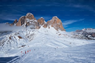 View of a ski resort piste with people skiing in Dolomites in Italy