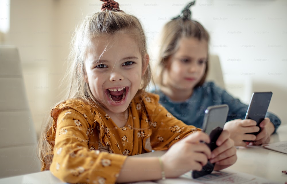 Spaß mit dem Telefon. Zwei kleine Schulmädchen mit Smartphone.