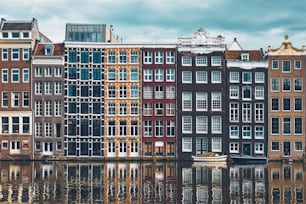 Row of typical houses and boat on Amsterdam canal Damrak with reflection. Amsterdam, Netherlands