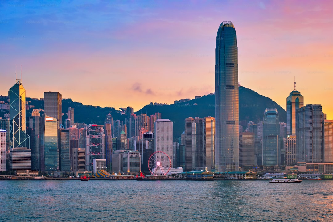Hong Kong skyline cityscape downtown skyscrapers over Victoria Harbour in the evening with junk tourist ferry boat on su