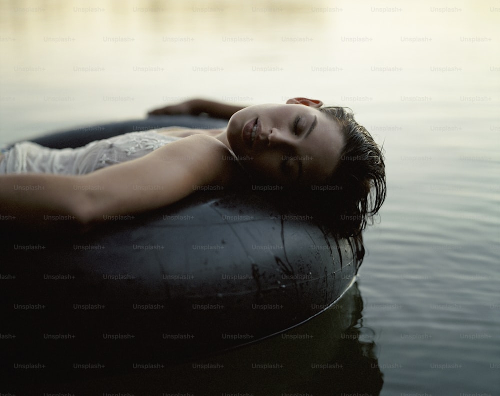 a woman laying on top of an inflatable object in the water