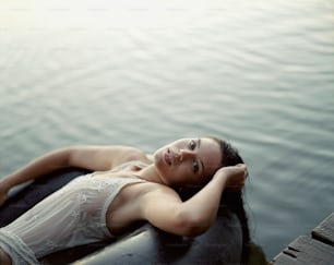 a woman laying on top of a body of water