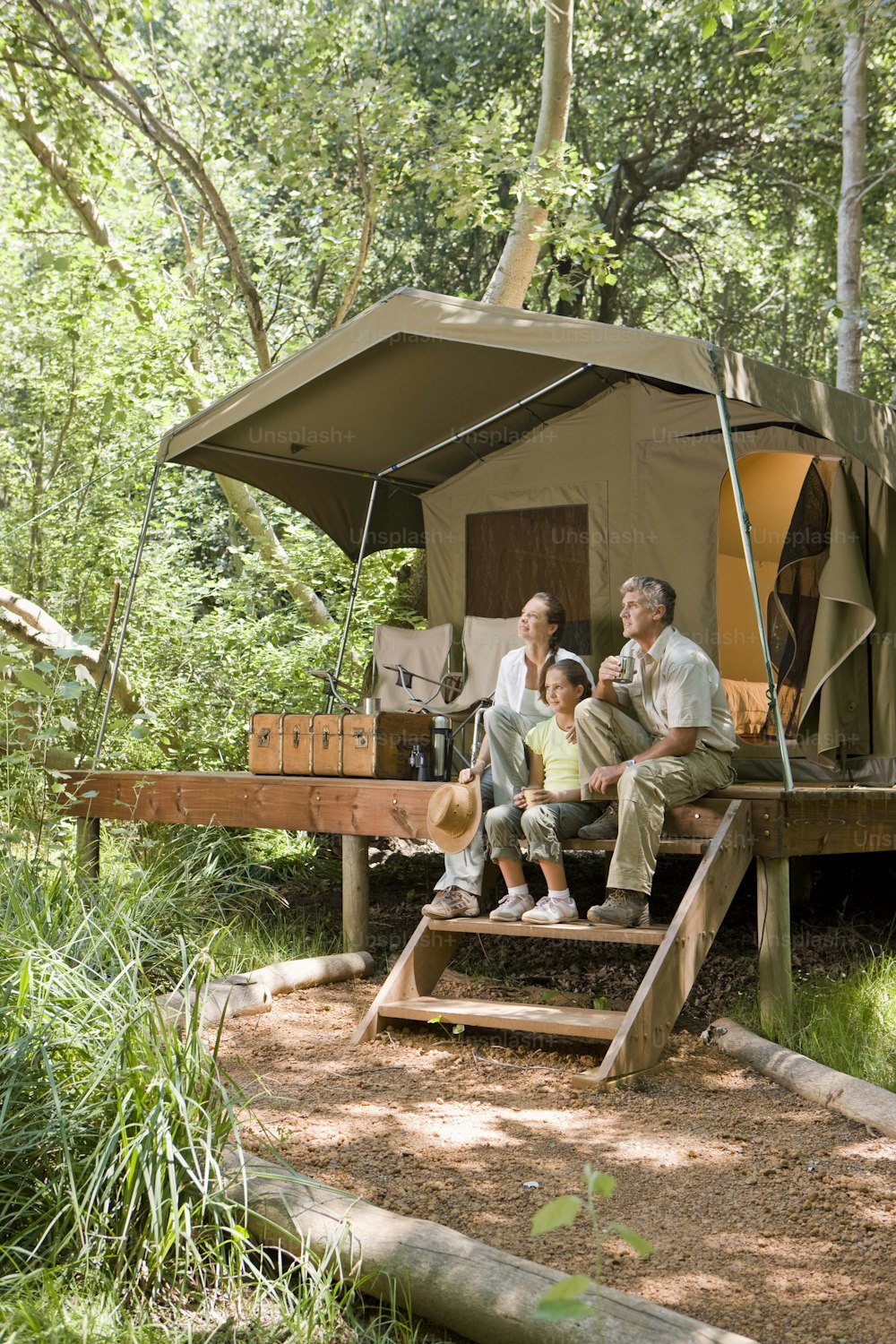 a man and two children sitting on a bench in front of a tent