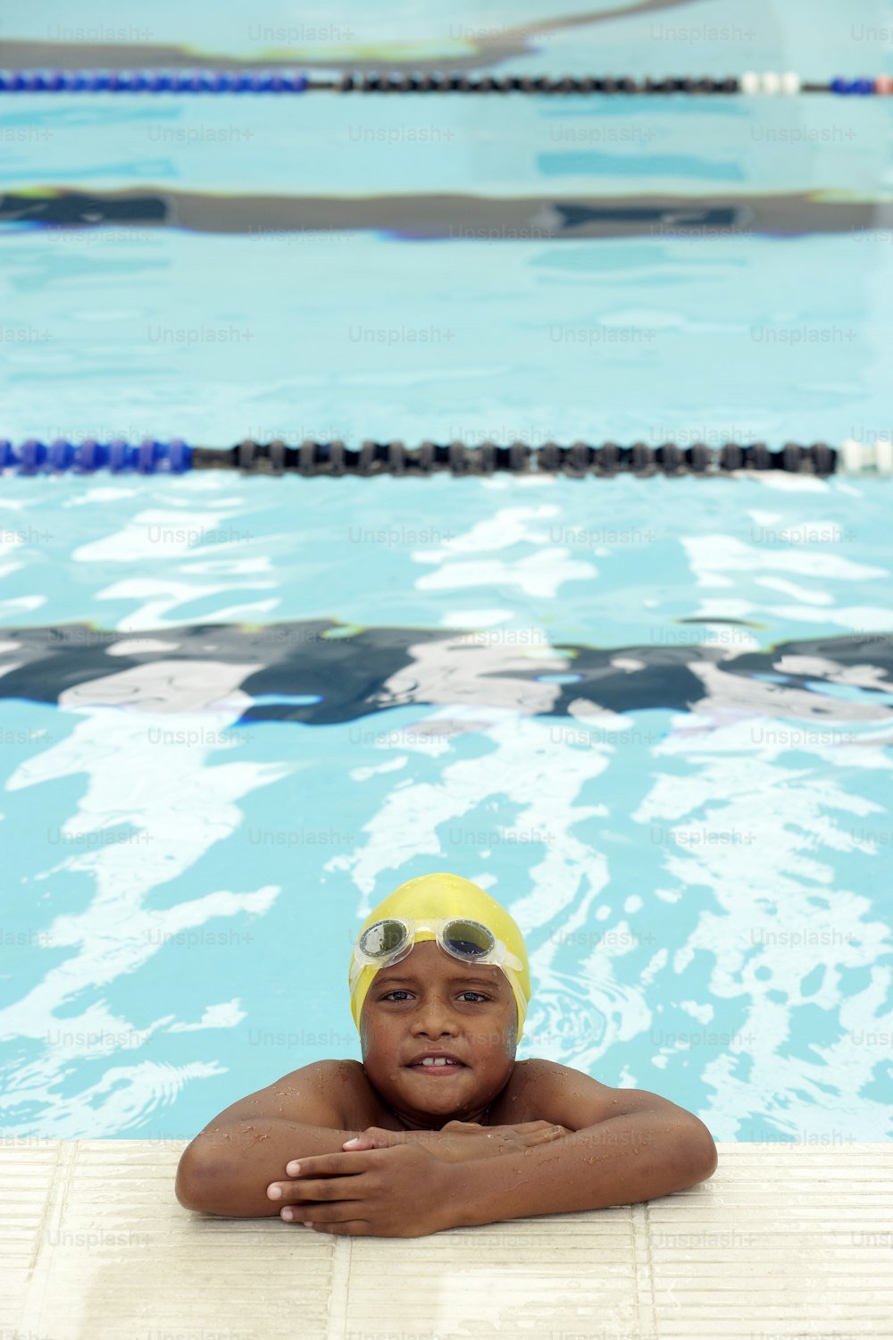 a young boy wearing a swimming cap and goggles