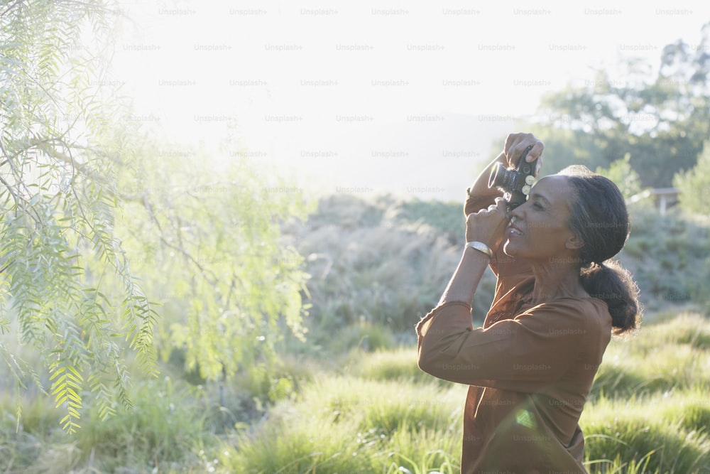 a woman taking a picture of a bird in a field