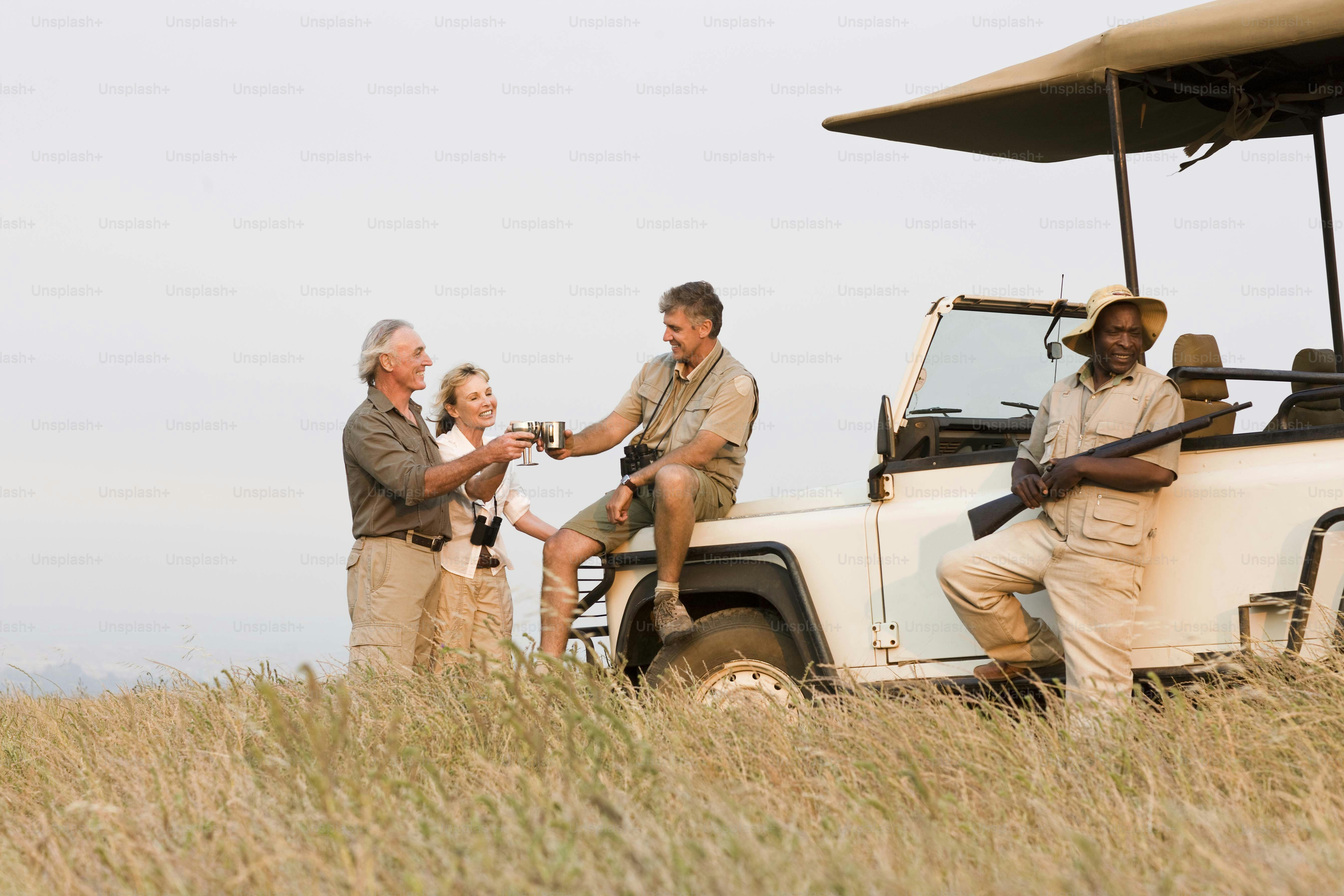 Un groupe de personnes debout à côté d’un véhicule de safari