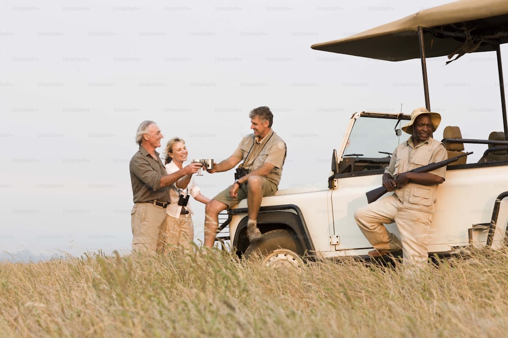 a group of people standing next to a safari vehicle