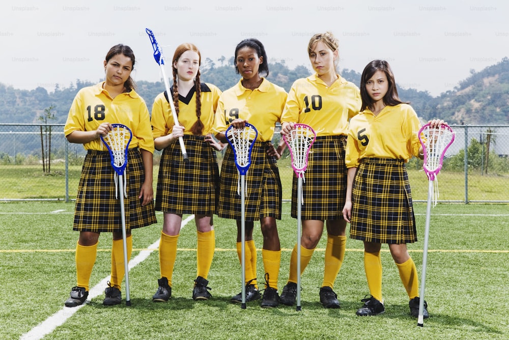 a group of girls in school uniforms holding lacrosse sticks