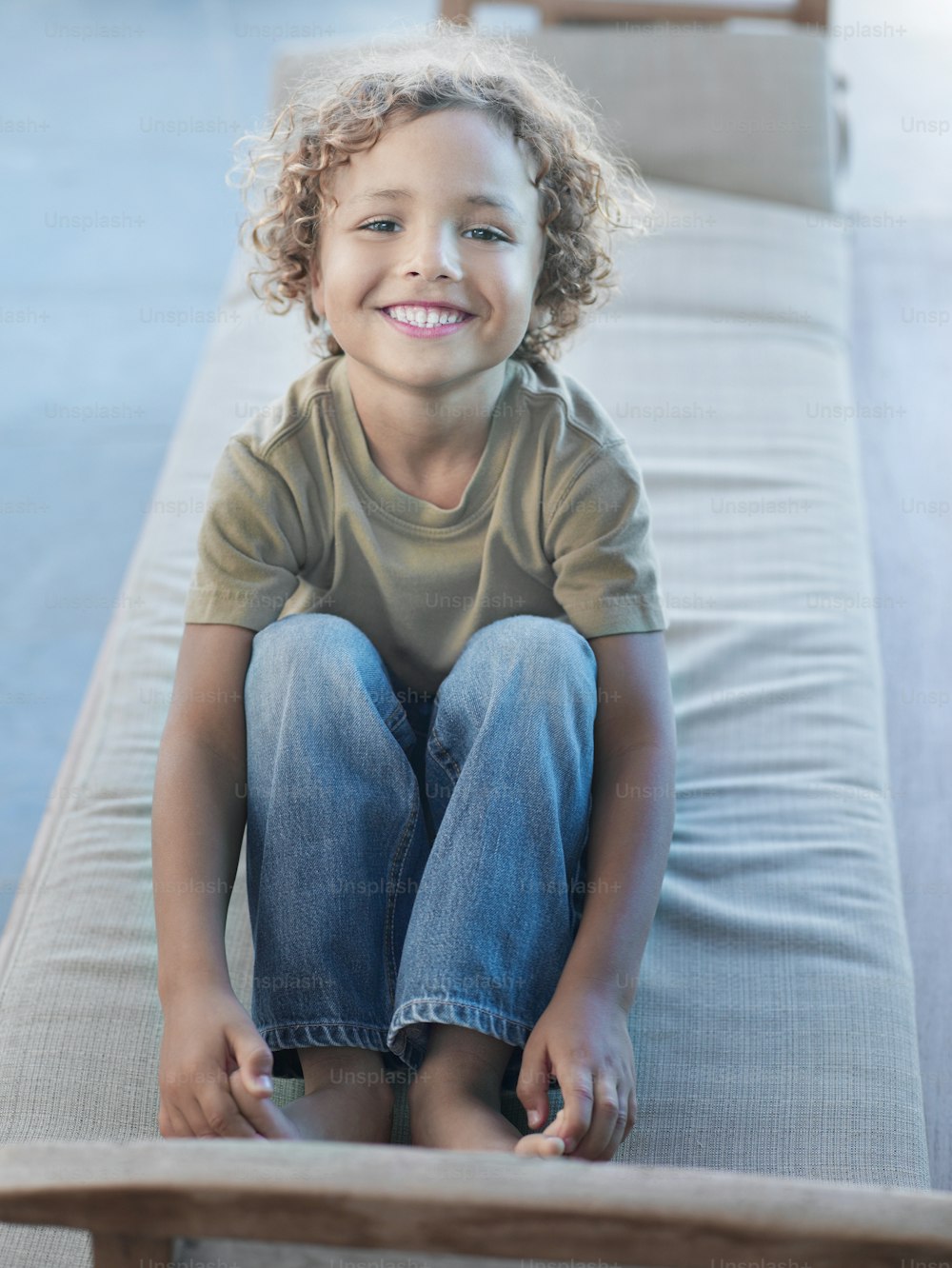 a little boy sitting on a couch smiling