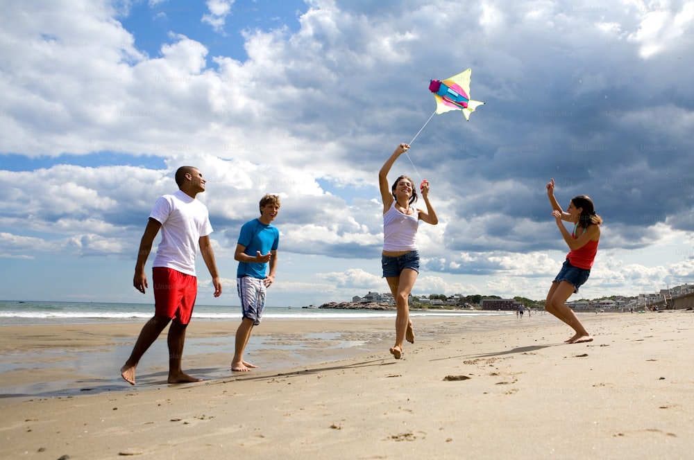 a group of people on a beach flying a kite