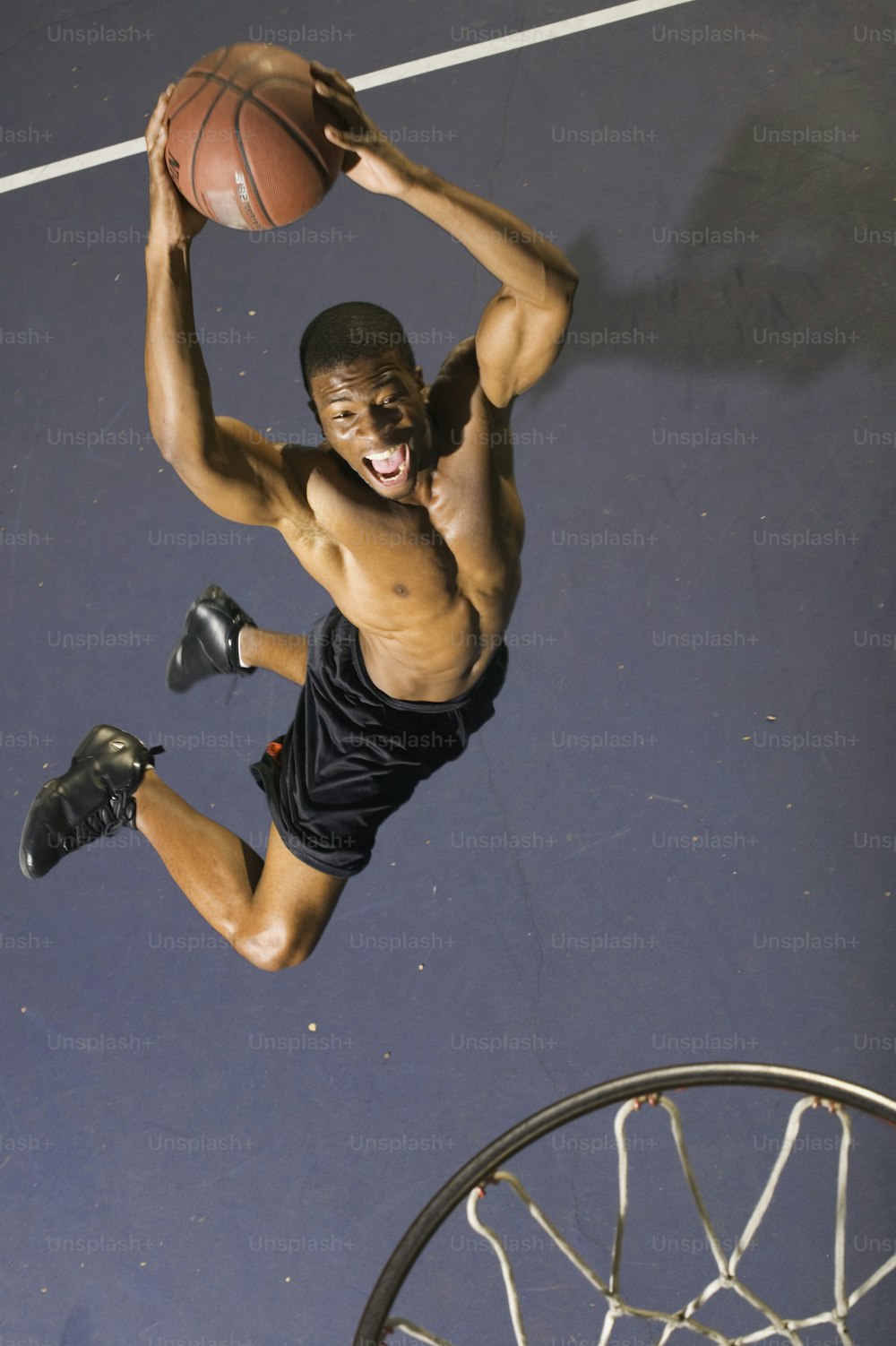 男がバスケットボールをダンクするために飛び上がっている