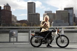 Una donna seduta su una moto che guarda il suo cellulare