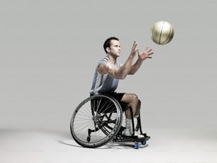 Un uomo su una sedia a rotelle lancia un pallone da basket