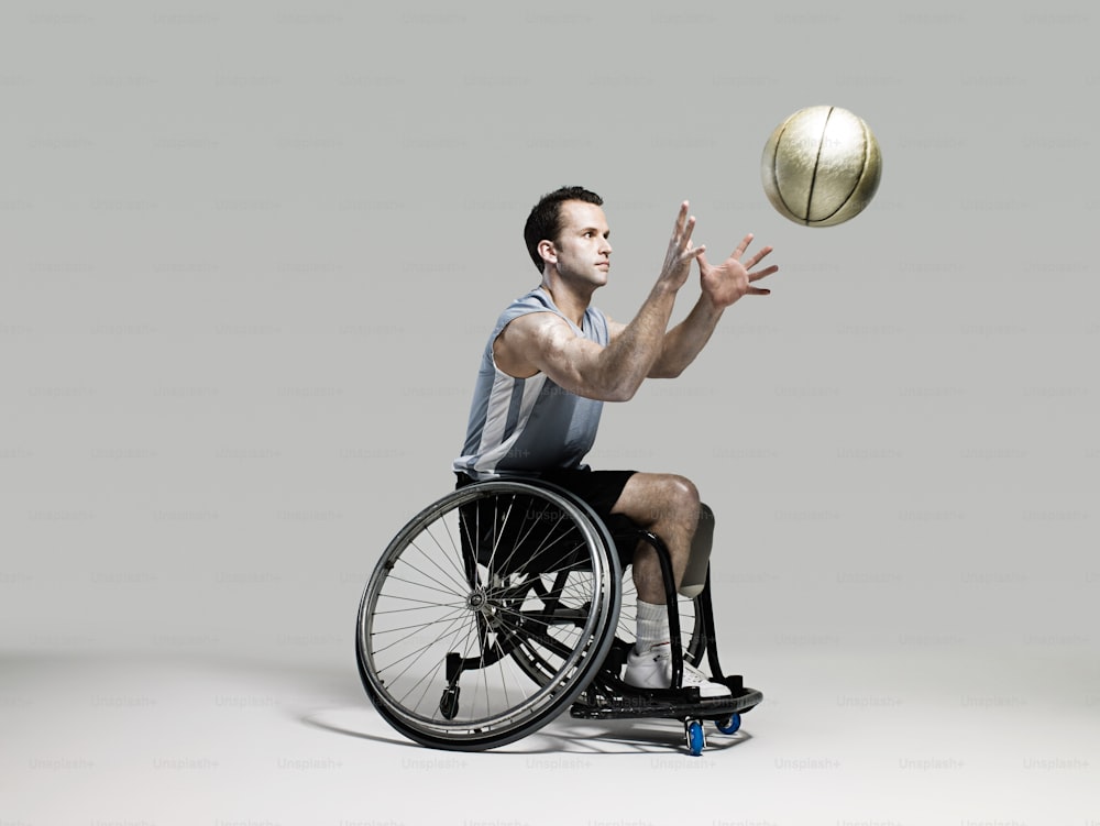 Un homme en fauteuil roulant lance un ballon de basket
