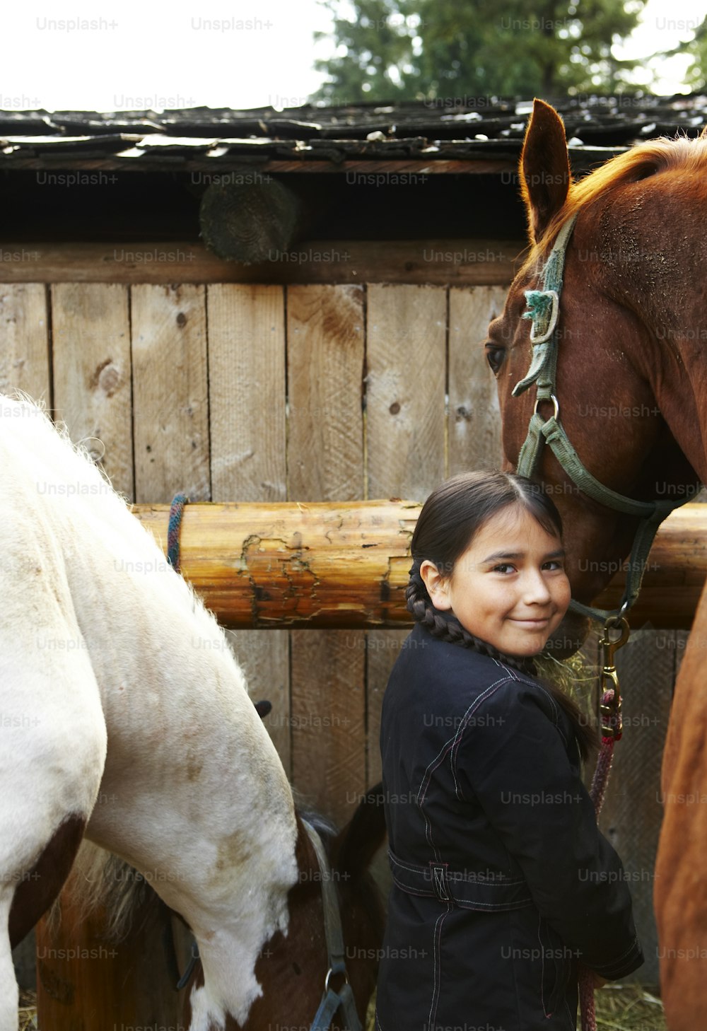 Ein junges Mädchen, das neben einem braunen und weißen Pferd steht