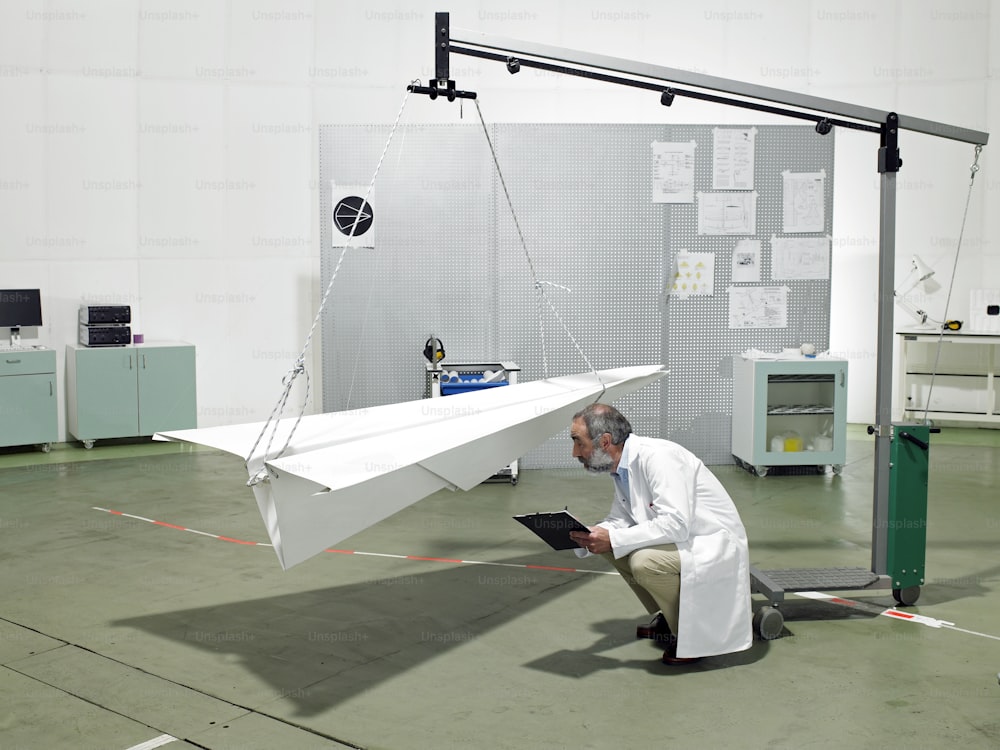 a man kneeling down next to a paper airplane