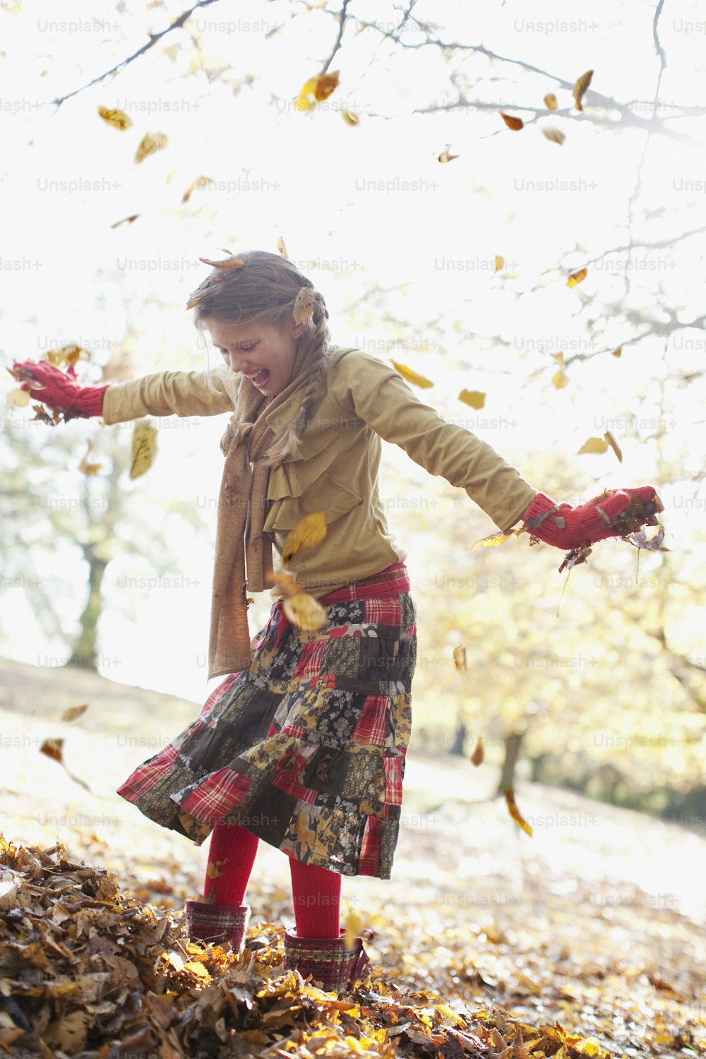 Una niña lanzando hojas al aire
