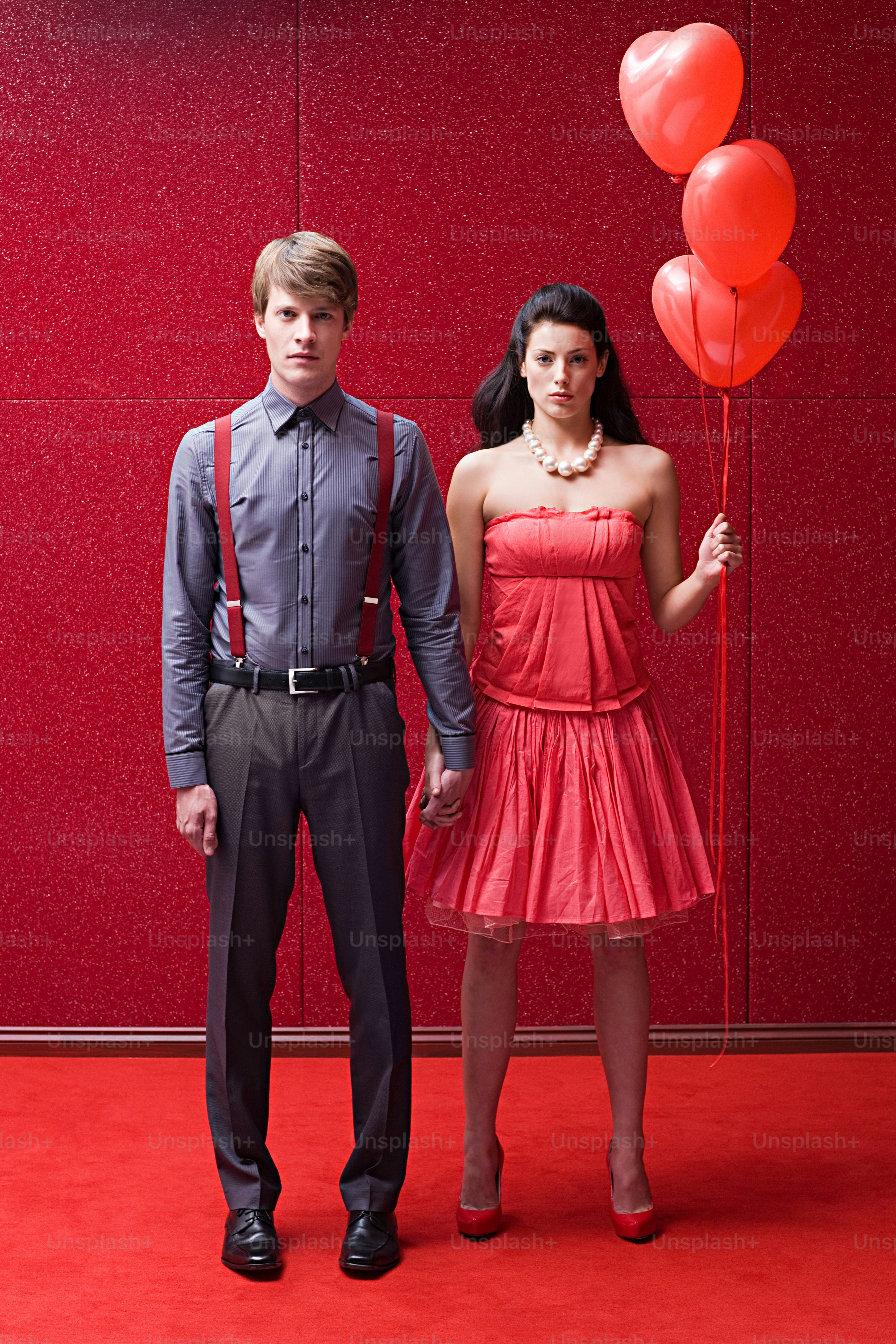 a man and a woman standing in front of a red wall