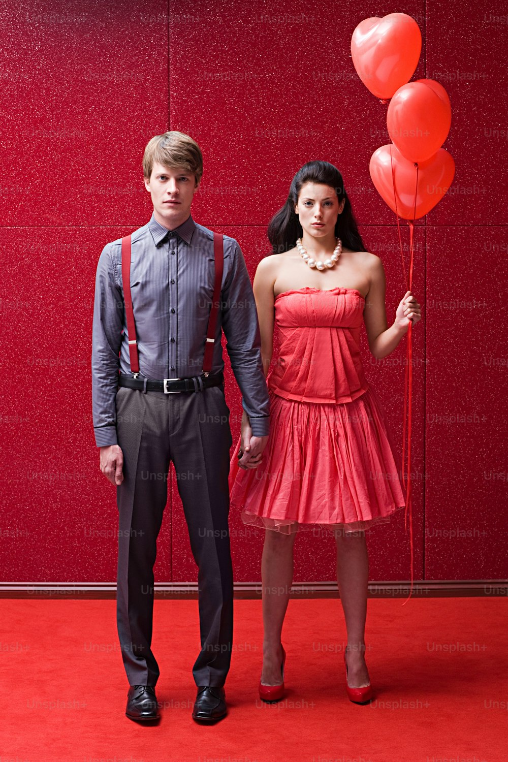 a man and a woman standing in front of a red wall