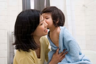 a woman kissing a little girl wrapped in a towel