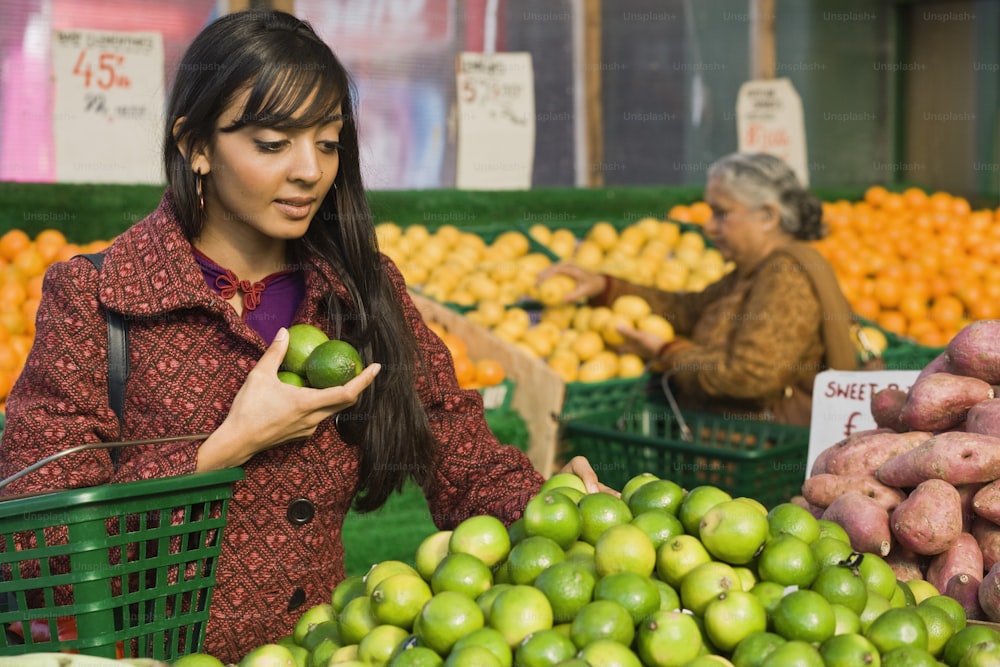 a woman standing in front of a display of fruit