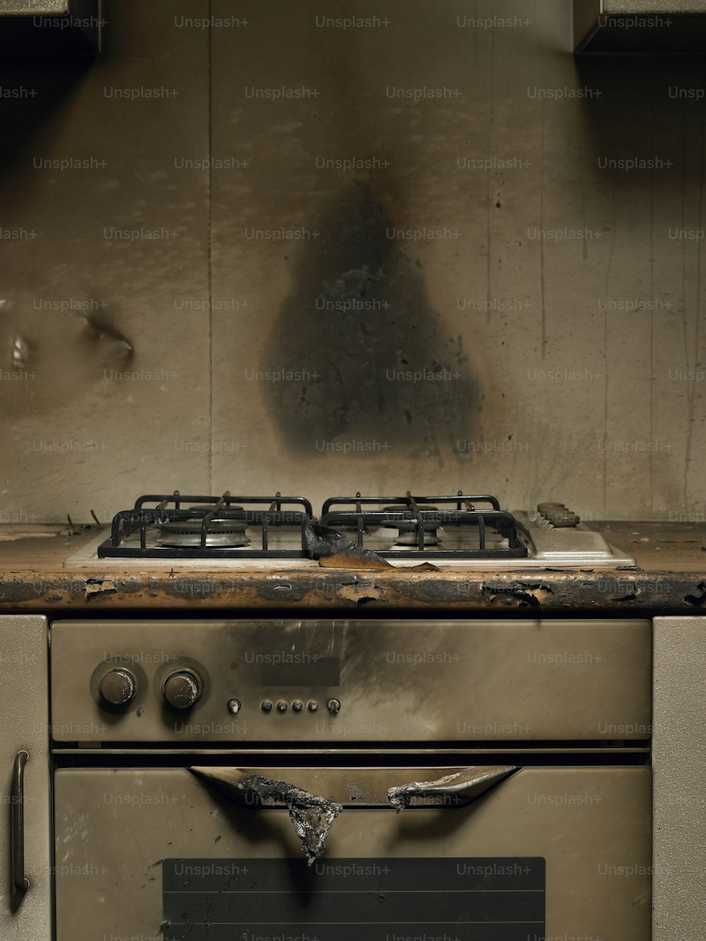 a dirty stove top oven in a dirty kitchen