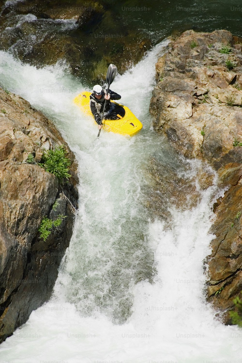 a man riding a yellow kayak down a river