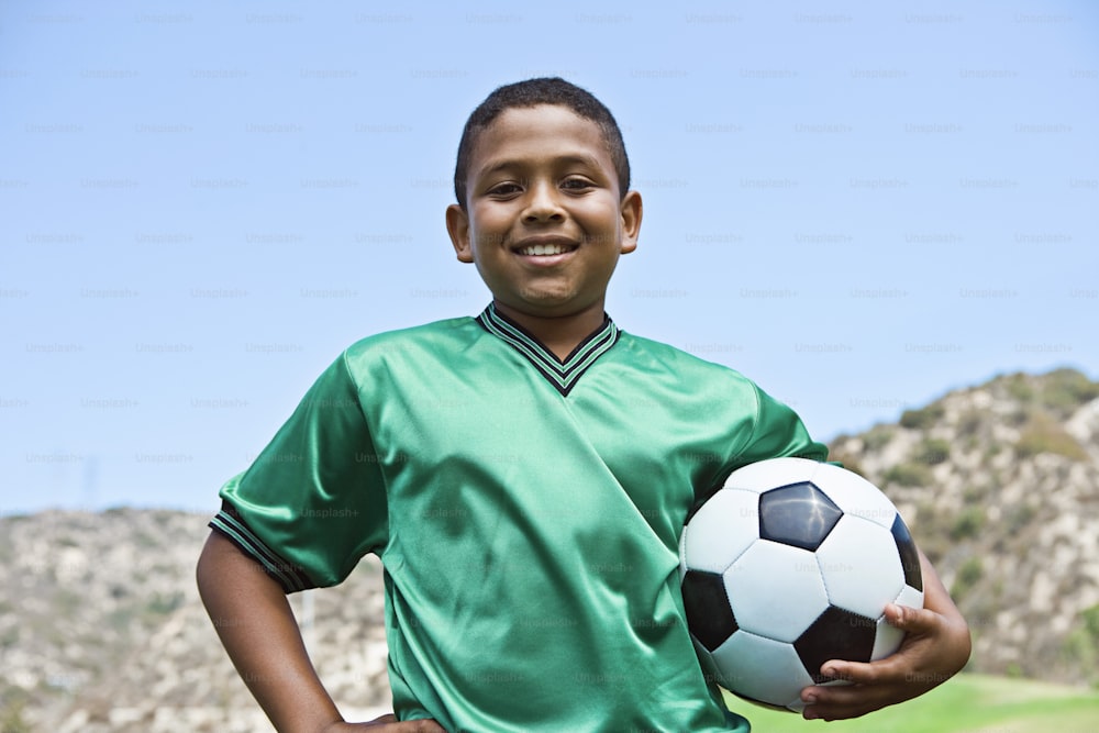 a boy in a green shirt holding a soccer ball