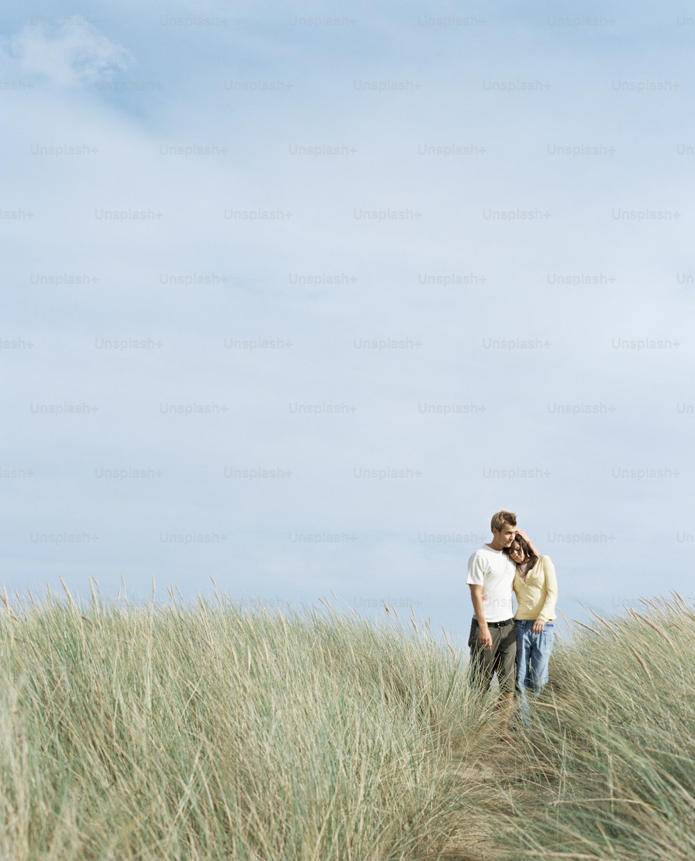 a man and woman standing in tall grass