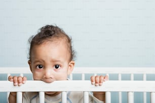 a baby in a crib looking over the top of the crib