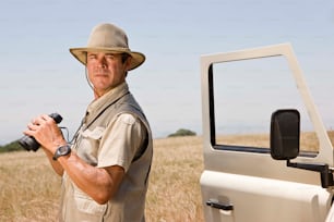 um homem de chapéu segurando uma câmera ao lado de um caminhão