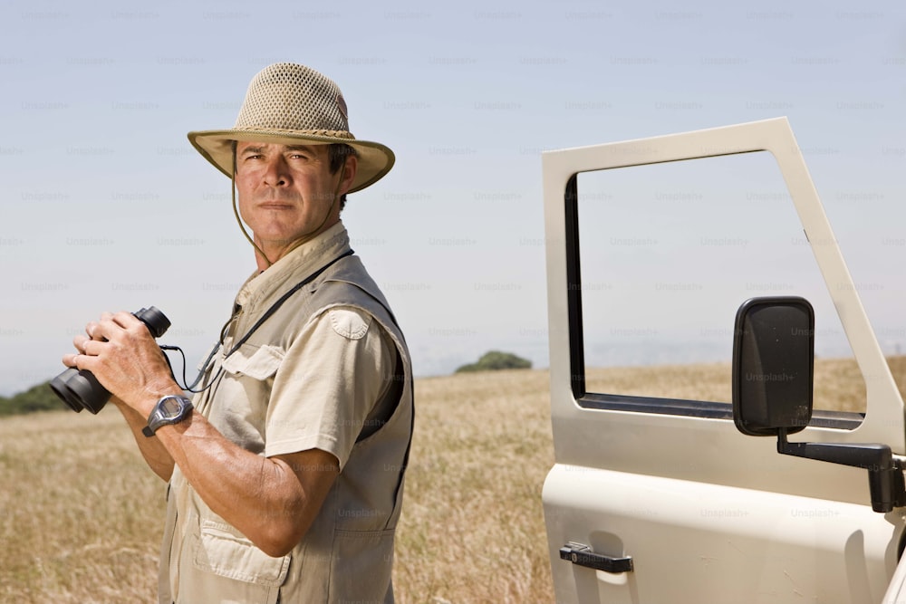 Un uomo con un cappello che tiene una macchina fotografica accanto a un camion