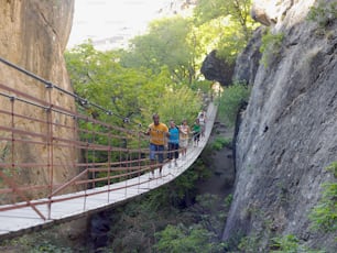 a group of people walking across a suspension bridge