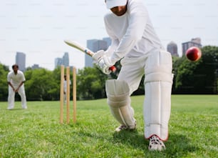 Un uomo in uniforme bianca che gioca una partita di cricket