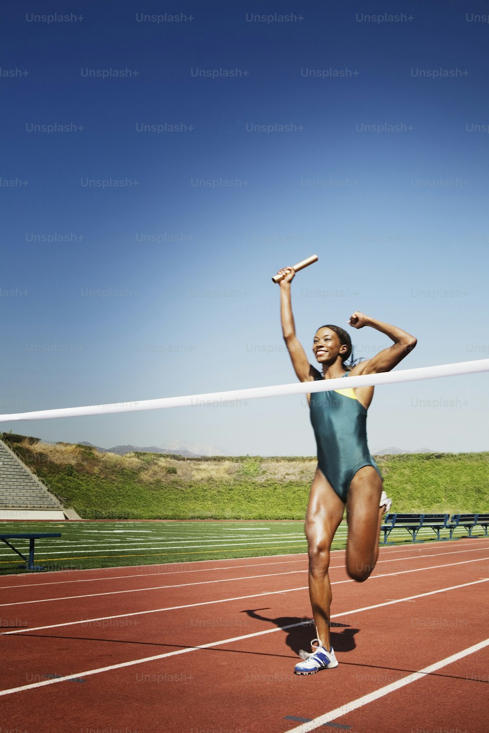 Una donna corre su una pista con le braccia in aria