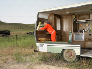 주황색 점프수트를 입은 남자가 트럭 뒤에 서 있다