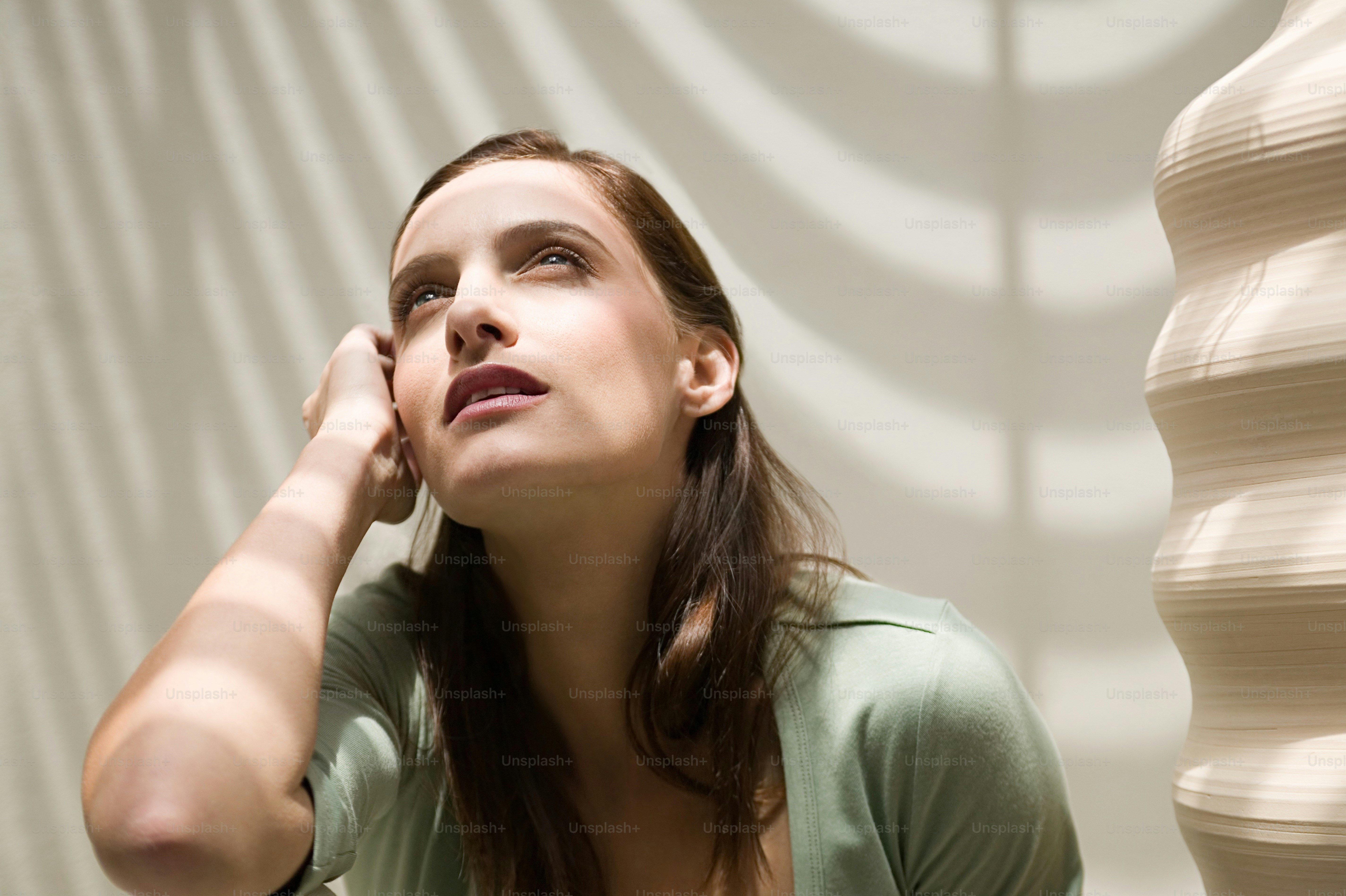 a woman sitting in front of a sculpture talking on a cell phone