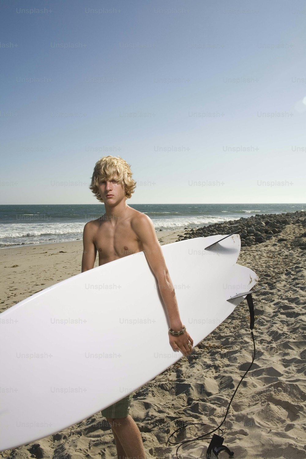 a man holding a white surfboard on a beach