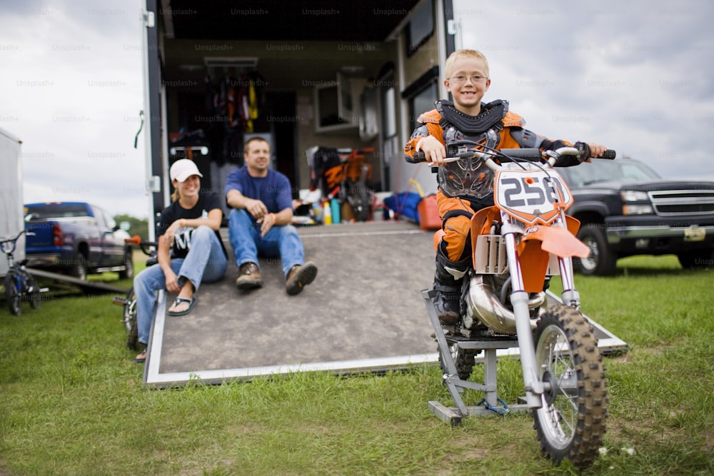 a young boy riding a dirt bike in front of a trailer