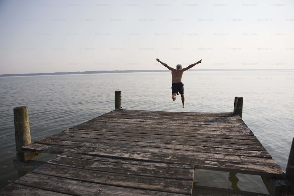 a man jumping off a dock into the water