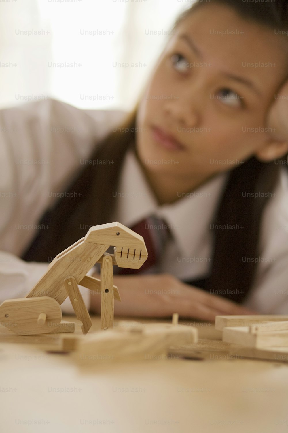 a young girl sitting at a table with a wooden toy horse