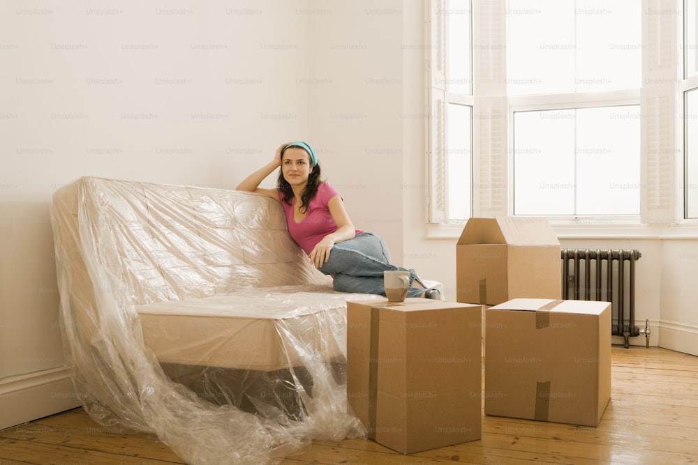 a woman sitting on a couch surrounded by boxes
