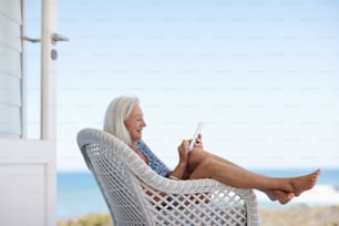 a woman sitting in a wicker chair with a cell phone