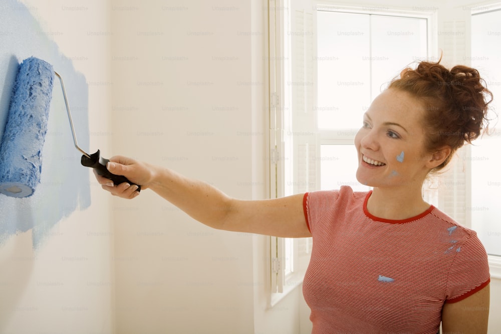 a woman is painting a wall with blue paint