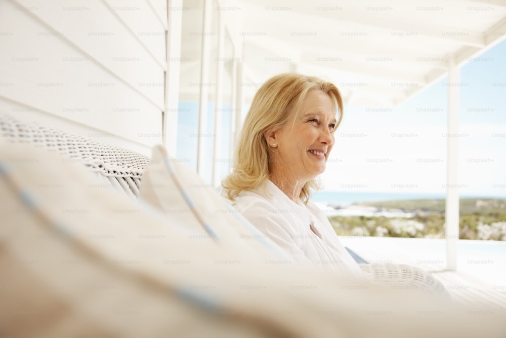 Donna pensionata felice che si rilassa sotto il portico durante una vacanza