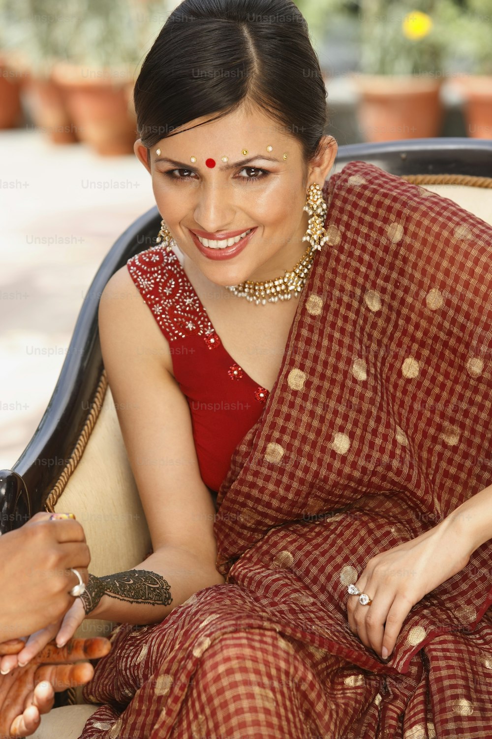 a woman in a red and gold sari sitting on a couch