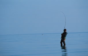 um homem parado na água com uma vara de pesca